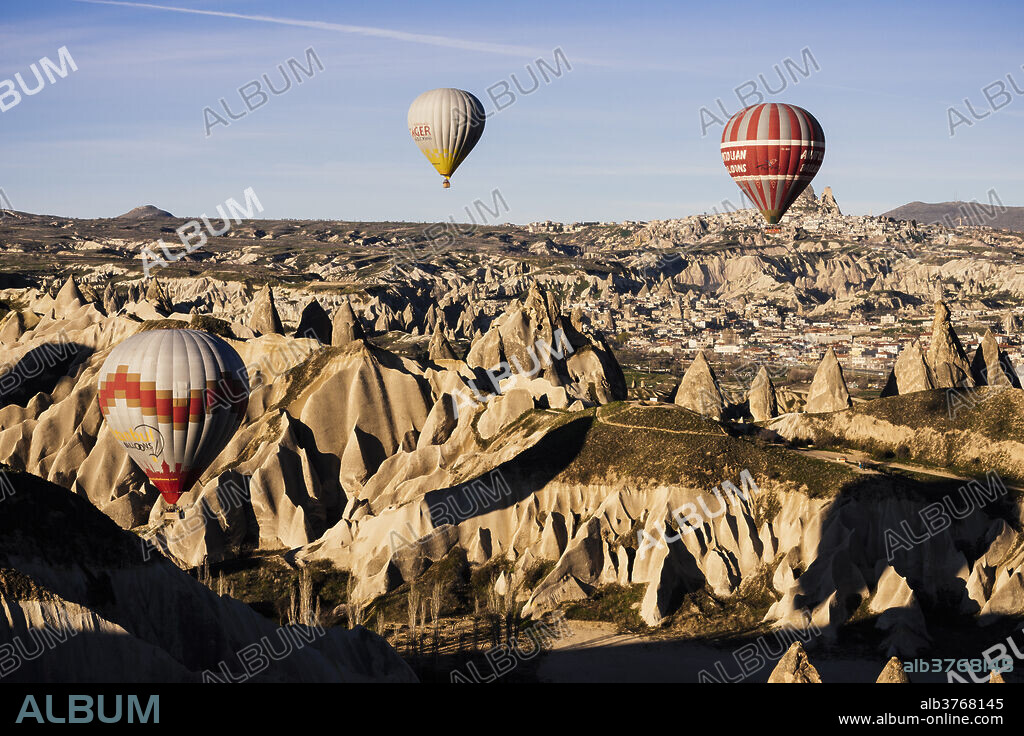 Hot air balloons flying among rock formations at sunrise in the Red Valley, Goreme National Park, UNESCO World Heritage Site, Cappadocia, Anatolia, Turkey, Asia Minor, Eurasia.