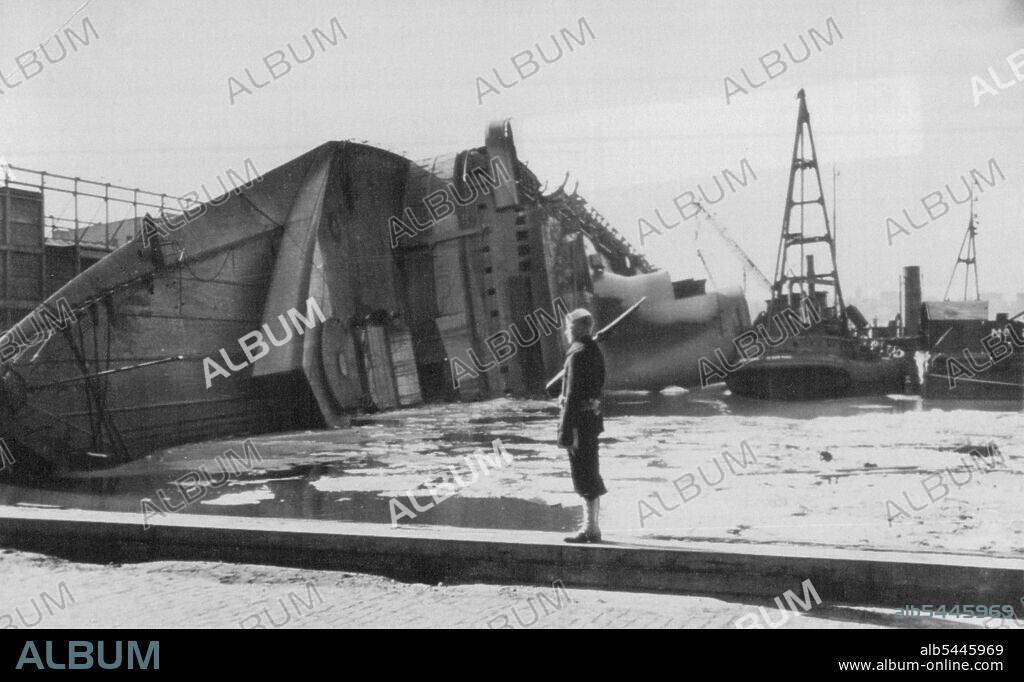 Normandie Quarded -- A U.S. sailor stands guard at one point of the pier slip where the Normandie lies on its side, victim of fire. Salvage tugs crowd about the liner -- renamed the Lafayette when the U.S. took it over. February 26, 1942. (Photo by AP Wirephoto).During World War II, Normandie was seized by U.S. authorities at New York and renamed USS Lafayette. In 1942, the liner caught fire while being converted to a troopship, capsized onto her port side and came to rest on the mud of the Hudson River at Pier 88.