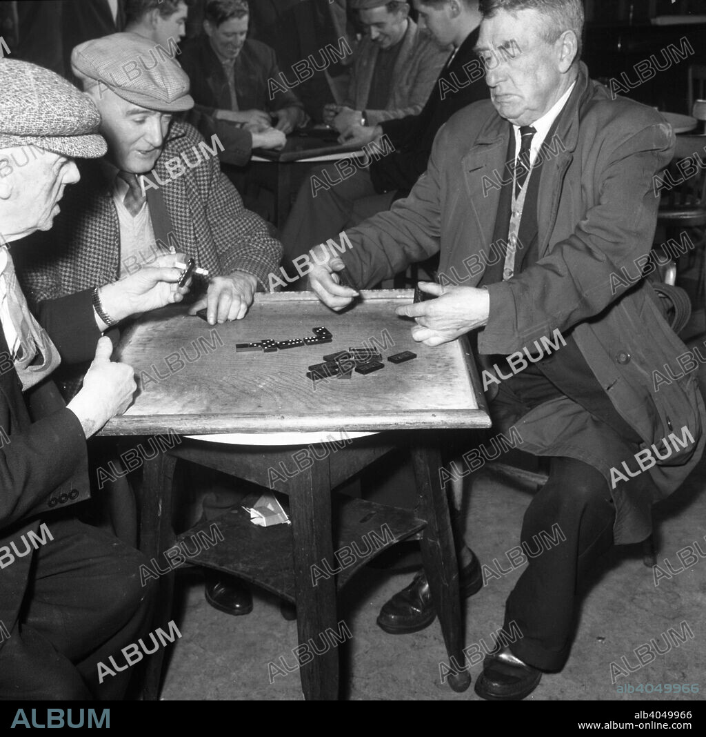 A game of dominoes in a miners' welfare club, Horden, County Durham, 1963. In a typical scene from a miners' welfare club, a man looks none too happy with his selection of dominoes, in this photograph taken for the National Coal Board (NCB).