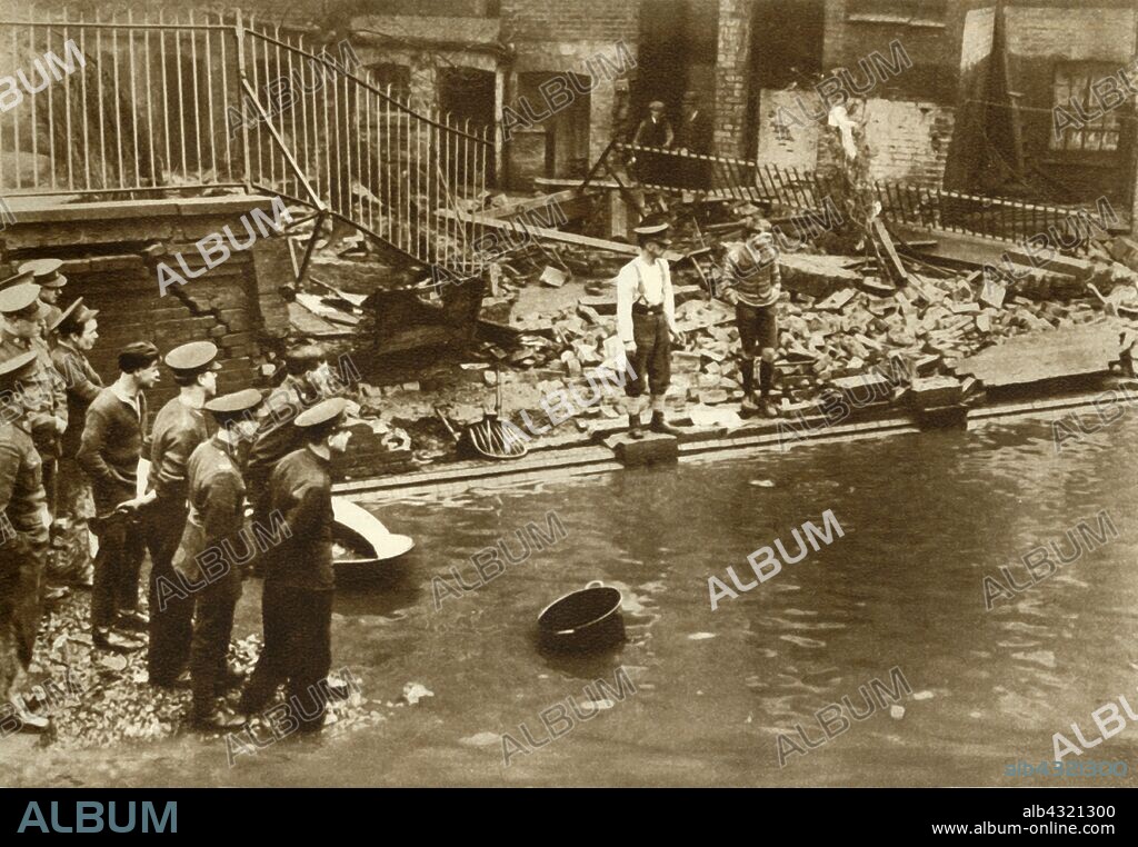 Flooding in London, 1928, (1935). 'Fourteen people were drowned as they slept in basement near the river and much damage was done to the surrounding property'. Flood waters poured over the top of the Thames Embankment and part of the Chelsea Embankment collapsed during the 1928 Thames flood. From "The Silver Jubilee Book - The Story of 25 Eventful Years in Pictures". [Odhams Press Ltd., London, 1935].