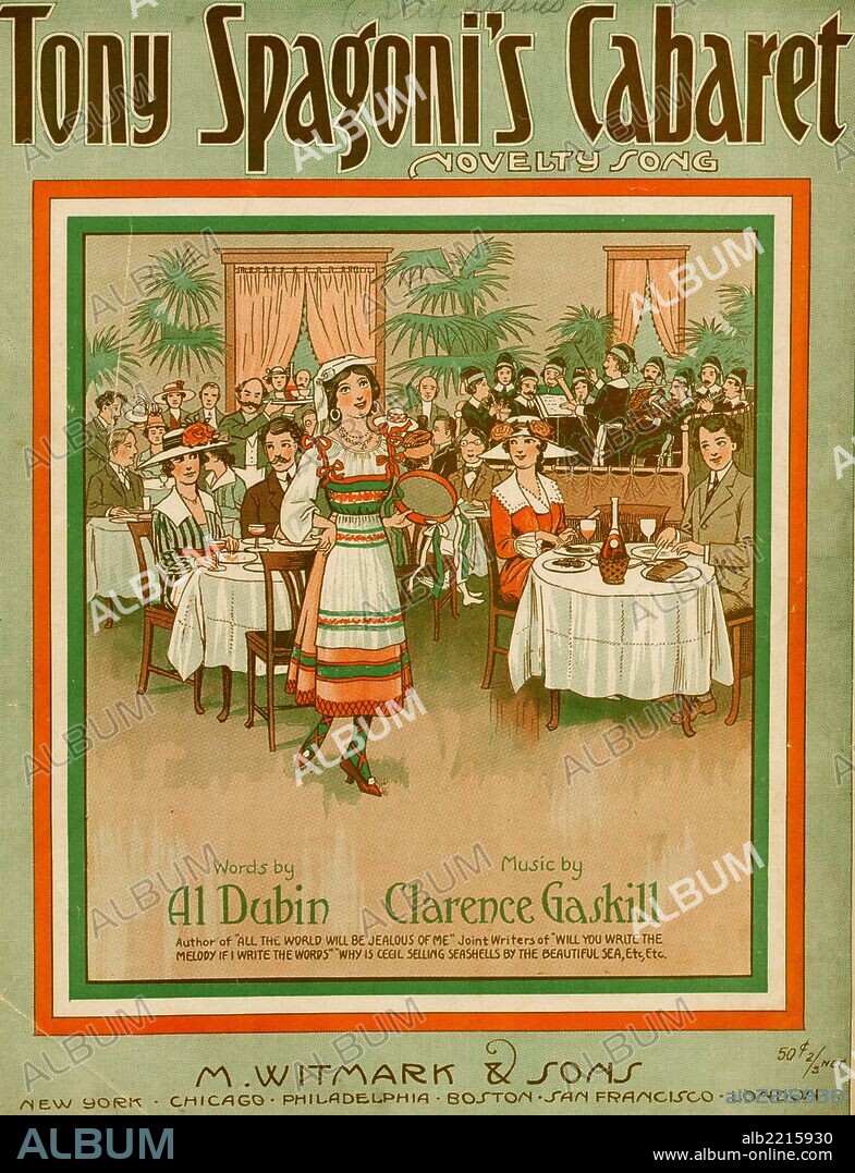 Girl  with tambourine dances in center floor of a cabaret with guests in formal type attire at the tables dining and a Chorus with musical conductor at the rear.