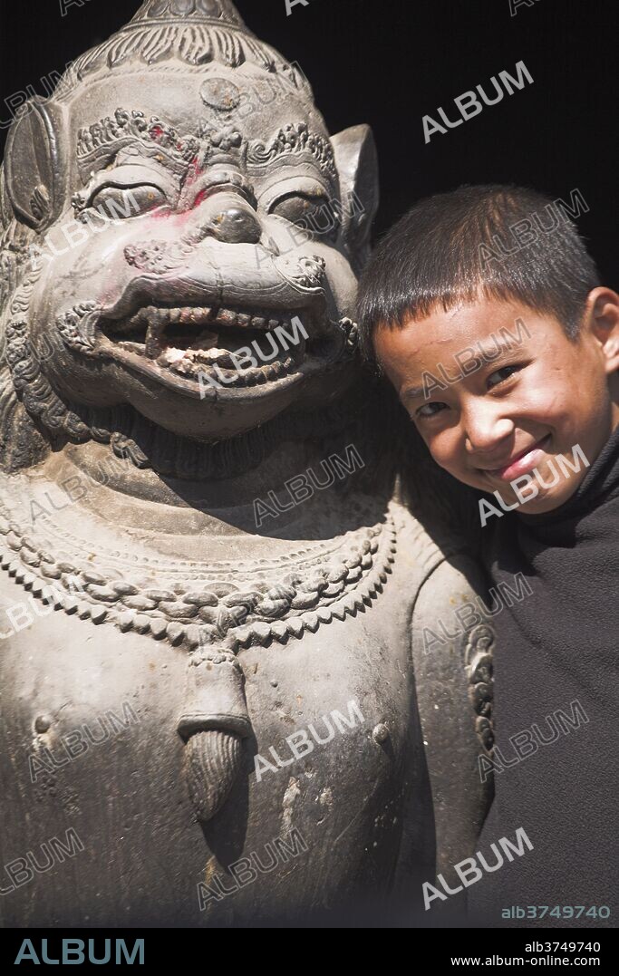 Boy stands by statue, Hanuman-Dhoka Durbar Square, UNESCO World Heritage Site, Kathmandu, Nepal, Asia.