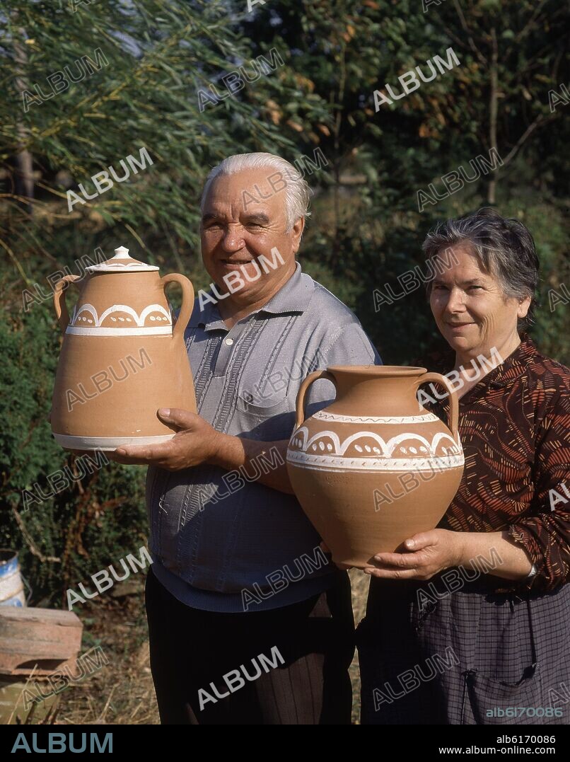 INDALECIO LOMBAO Y ESPOSA CON SELLA Y CANTARO DE CERAMICA EN LAS MANOS.