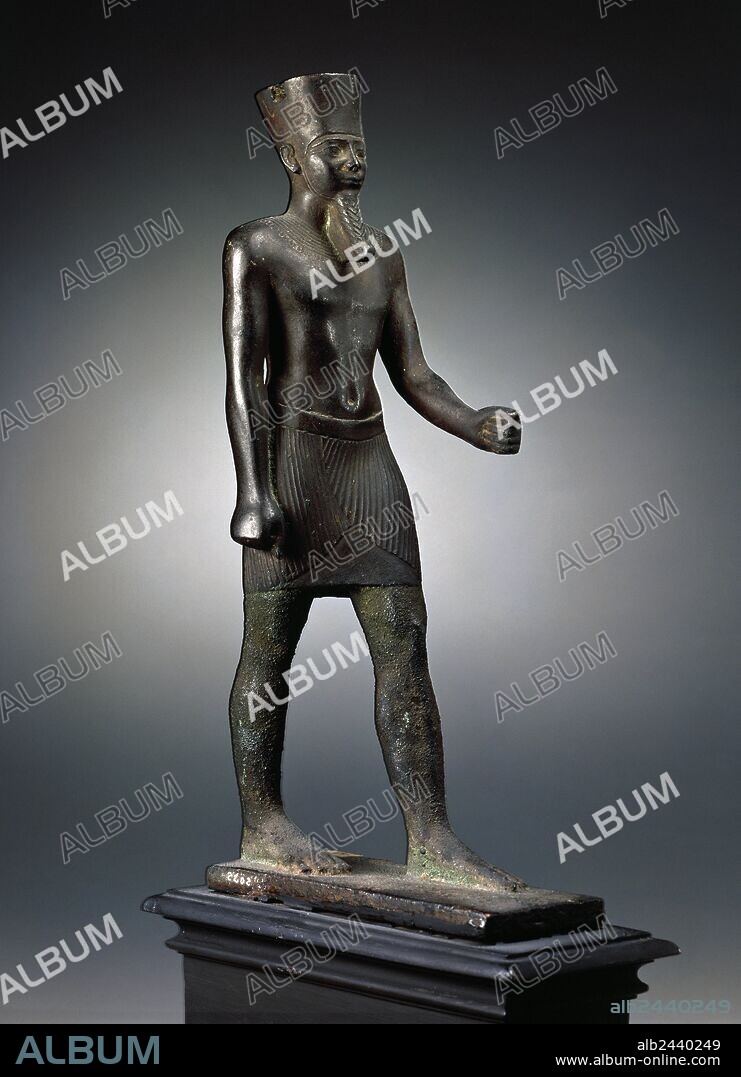 Arte Egipcio. Estatuilla de bronce que representa al dios Amón de pié, con la pierna y el brazo adelantados sujetando un cetro actualmente desaparecido. Tocado con corona que ha perdido las dos plumas, viste faldellín y lleva barba postiza. Fechado entre 664-332 A. C. Bajo Imperio. Museo Arqueológico Nacional. Madrid. España.