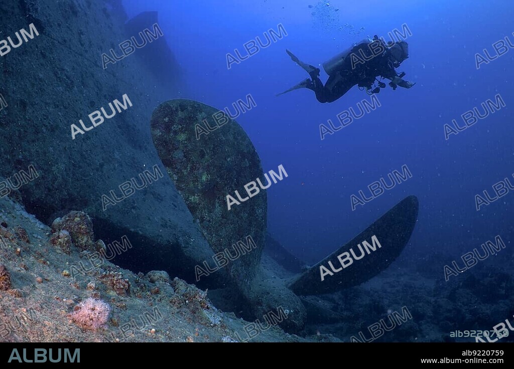 Thistlegorm propeller from the Second World War on the seabed. Divers in the background. Dive site Thistlegorm wreck, Sinai, Egypt, Red Sea, Africa.