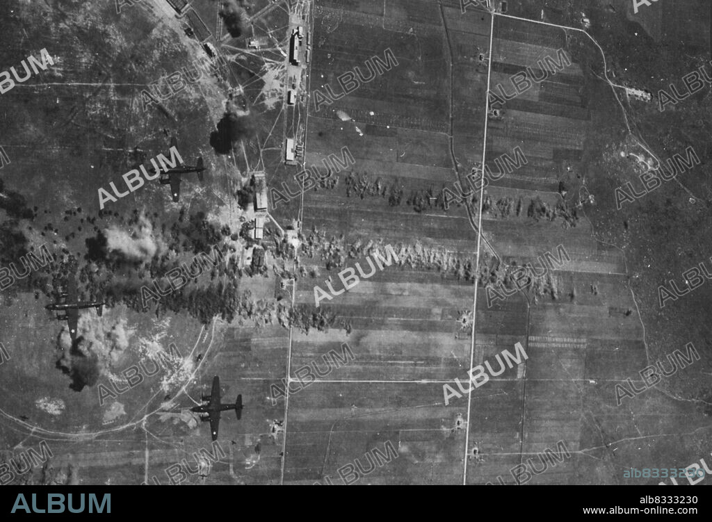 Alghero, Sicilian Airfield Raided By Allied Bombers -- Bombs falling on airfield runways, buildings and dispersed aircraft during a raid on Alghero airdrome, Sicily, about May 25th. Approximately 25 bombers took part in this raid. There of them B.26 (Martin Marauders) of the U.S.A.S.F. can be seen in photo. June  14, 1943. (Photo by U.S. Official Photo).
