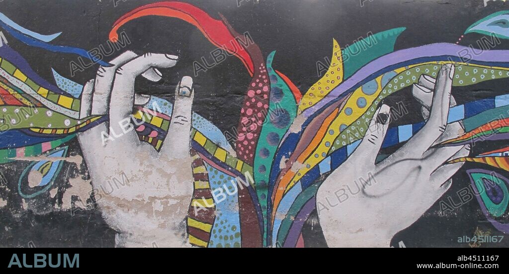Ilustración de dos manos entrelazando entre los dedos cintas de colores estampadas; graffiti mural, Barrio Raval, Distrito Ciudad Vieja, Barcelona en 2014.