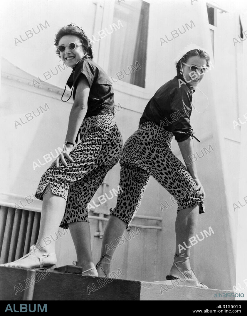 New York,  New York: 1953. Two sisters sport matching leopard-skin toreador pants upon their arrival aboard the liner Queen Elizabeth in New York.