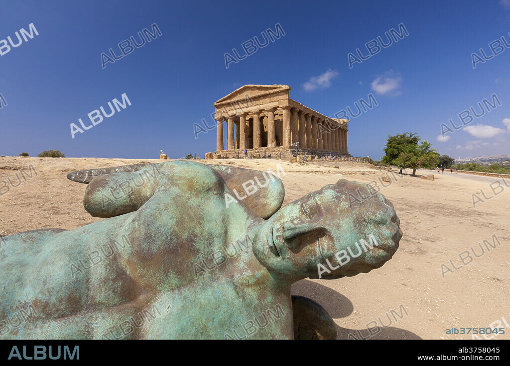 Bronze statue of the fallen Icarus frames the ancient Temple of Concordia, Valle dei Templi, Agrigento, UNESCO World Heritage Site, Sicily, Italy, Europe.