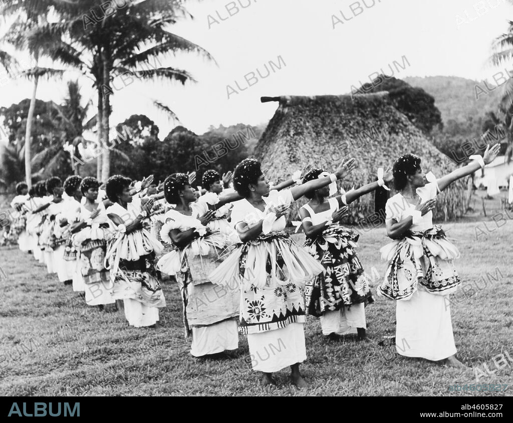 Fiji, Fijian dancers at NasilaiA large group of Fijian women perform a traditional dance outdoors. Dressed in ceremonial costume including tiered 'masi' (bark cloth) skirts, they dance in formation, turning their heads and stretching their arms out to one side. , 1965. 2005/010/1/14/89.