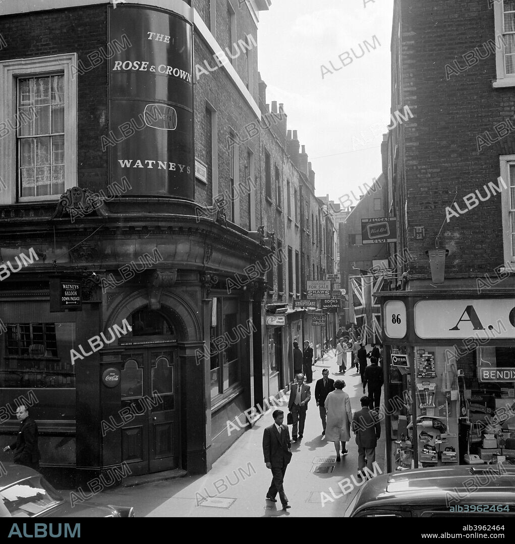 St Anne's Court, Soho, City of Westminster, London, early 1960s. View along the street showing signs for clubs and shops, with the corner of the Rose and Crown pub, Dean Street, in the foreground.