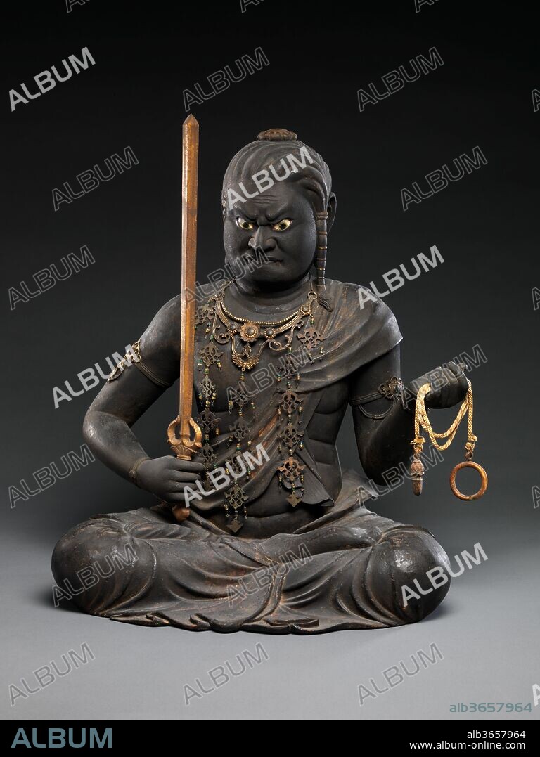 Fudo Myoo. Artist: Kaikei (Japanese, active 1183-1223). Culture: Japan. Dimensions: H. 21 in. (53.3 cm); H. to top of sword 21 1/2 in. (54.6 cm); W. 16 3/4 in. (42.5 cm); D. 15 in. (38.1 cm). Date: early 13th century.
Fudo Myoo (Sanskrit: Acala-vidyaraja), the chief of the Five Wisdom Kings (Godai myoo), is the wrathful avatar of Dainichi Buddha and the tenacious protector of Buddhist law. His iconography, drawn from the Dainichi Sutra, describes his body as black or blue, with bulging eyes, protruding fangs that bite his lower lip, and hair that hangs down his left shoulder. He carries in his left hand a lasso to catch and bind demons (obstacles to awakening) and in his right hand a sword to decapitate them (cut through ignorance). 
The present example, from the workshop of Kaikei, one of the leading sculptors of his day, adheres to this iconography. Traces of colored pigments and strips of cut gold (kirikane) are visible in the deity's robes, and his eyes are inlaid with crystal, intensifying his ferocious expression.