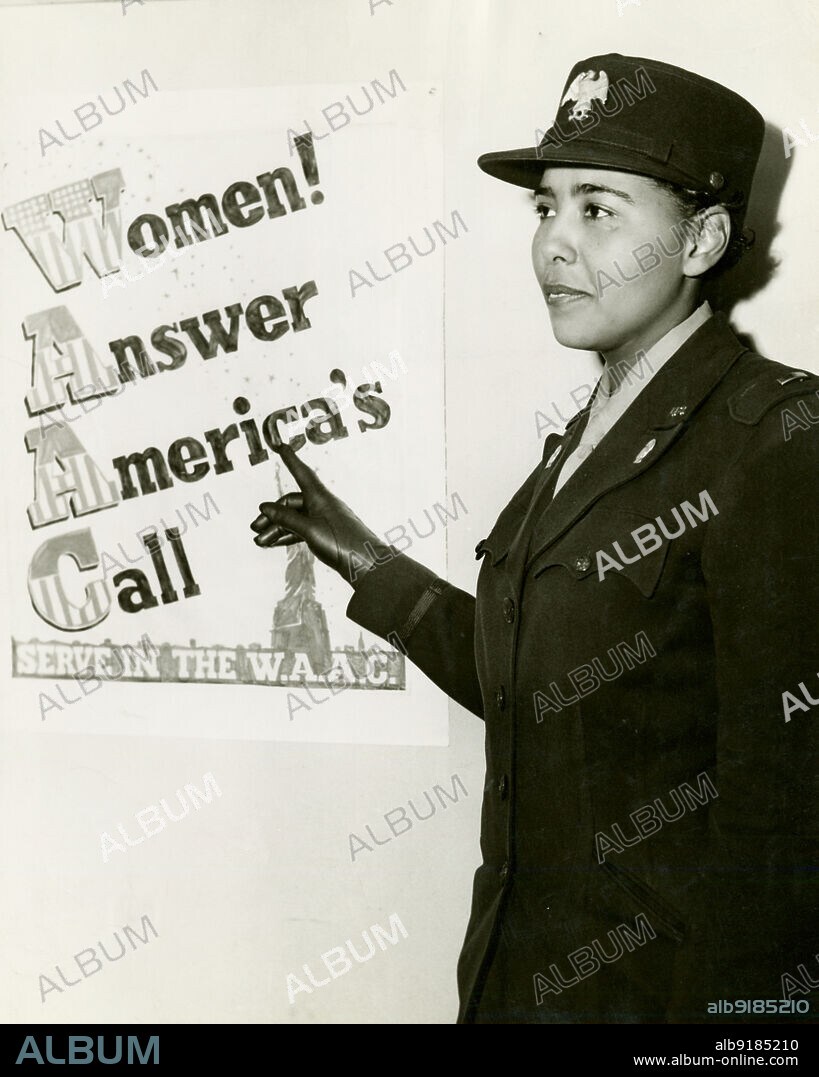UNITED STATES ARMY. African American Charity Adams, First Officer in the Women's Army Auxiliary Corps, standing in uniform and pointing to a poster that reads, "Women! Answer America's Call, Serve in the W.A.A.C.", 1943-02.