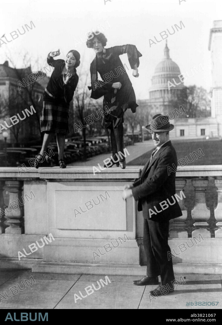 Rep. T.S. McMillan of Charleston, S.C. with flappers, Miss Ruth Bennett and Miss Sylvia Clavins, who are doing the Charleston on railing, with U.S. Capitol in background, 1926. Flappers were a new breed of young Western women in the 1920s who wore short skirts, bobbed their hair, listened to jazz, and flaunted their disdain for what was then considered acceptable behavior. Flappers were seen as brash for wearing excessive makeup, drinking, treating sex in a casual manner, smoking, driving automobiles and otherwise flouting social and sexual norms. Developed by Kathryn Wilson, the Charleston became a popular dance craze in the wider international community during the 1920s. Despite its origins, the Charleston is most frequently associated with white flappers and the speakeasy. Here, these young women would dance alone or together as a way of mocking the citizens who supported the Prohibition amendment, as the Charleston was then considered quite immoral and provocative.