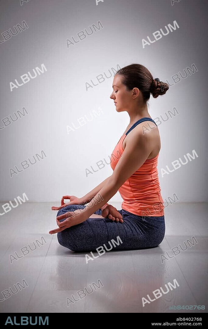Beautiful fit yogini woman meditating in yoga asana Padmasana (Lotus pose) cross legged position for meditation with Chin Mudra, psychic gesture of consciousness.