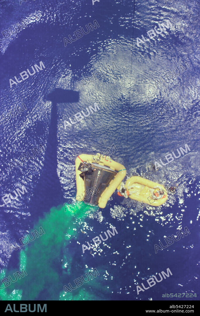 Gemini 4 Recovery with Green Marker Dye, 1965. Overhead view of the Gemini 4 spacecraft showing the yellow flotation collar used to stabilize the spacecraft in choppy seas. The green marker dye is highly visible from the air and is used as a locating aid. A crewmember is being hoisted aboard a U.S. Navy helicopter during recovery operations following the successful four-day, 62 revolution mission highlighted by Ed White's space walk.