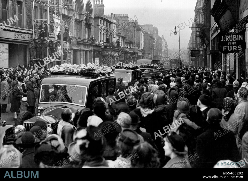 Funeral Of Tommy Handley: Crowds pay respects to Tommy Handley. A general view showing the funeral procession leaving Westbourne Grove for Golders Green Crematorium. The funeral cortege of Tommy Handley of "ITMA" fame, left from a private chapel in Westbourne Grove, London, to-day (Thursday) for Golders Green Crematorium where the funeral service was relayed to the crowds outside. January 13, 1949. (Photo by Reutersphoto).