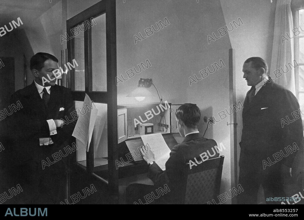 STOCKHOLM 1926.. Not. 1926 Väderlekstjänsten. Rapporten läses av G. Holmqvist tv. Anders Ångström th. C.J.Östman. Tidigaste bilden av en utsändning. Mikrofonen, kallades för sockerbiten. Var från 20-talet. Anm. Inspelningar Studios Meteorologer Publ. i boken Hört och Sett sid.30 CD343 persons: CJ ÖSTMAN;ANDERS ÅNGSTRÖM;G HOLMQUIST sites: STOCKHOLM;SVERIGE.