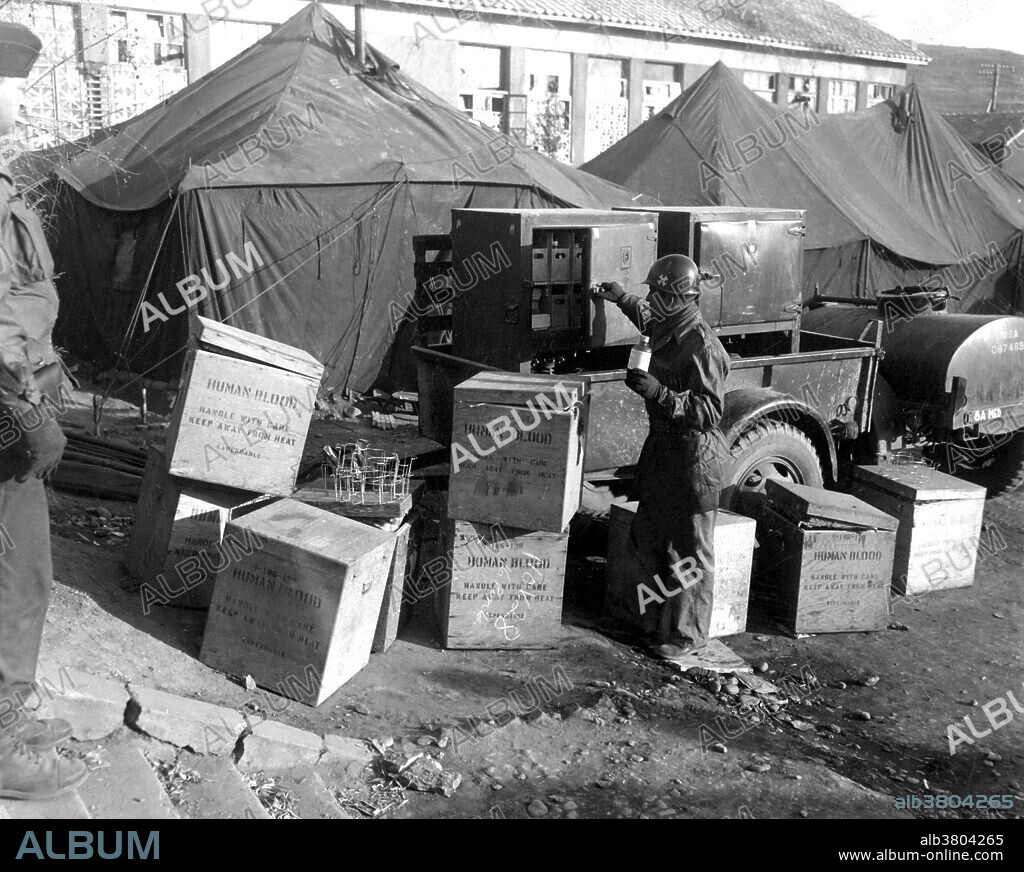 Caption: "M/Sgt. George Miller selects human blood for patient at the 8076th Mobile Army Surgical Hospital at Kunr-ri, Korea. November 27, 1950." The Mobile Army Surgical Hospital (MASH) refers to a United States Army medical unit serving as a fully functional hospital in a combat area of operations. The units were first established in August 1945, and were deployed during the Korean War and later conflicts. It was designed to get experienced personnel closer to the front, so that the wounded could be treated sooner and with greater success. Casualties were first treated at the point of injury through buddy aid, then routed through Battalion Aid Stations for emergency stabilizing surgery, and finally routed to the MASH for the most extensive treatment. This proved to be highly successful; during the Korean War, a seriously wounded soldier who made it to a MASH unit alive had a greater than 97% chance of survival once he received treatment. Photograph credited to Corporal Fred Rice, U.S. Army.