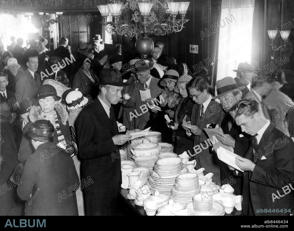 ©SCANPIX SWEDEN, 1939-09-06.. Kreugerkraschen - efterdyningar.. Kreugerkoncernen försattes i konkurs, som helt avslutades först 1941. Bilden är från visningen av Kreugers våning. Ivar Kreuger sköt sig i Paris 12 mars 1932. Människor, bläddrande i häften, trängs runt ett bord fyllt med porslin i travar.. Foto: Scanpix. Code: 20360.