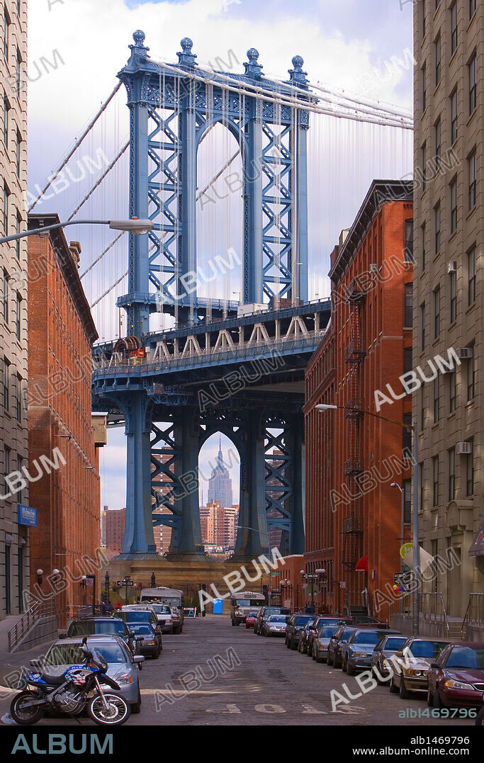 Vista parcial del PUENTE DE MANHATTAN (MANHATTAN BRIDGE), al fondo, entre dos edificios. A través del arco se aprecia el EMPIRE STATE. NUEVA YORK. Estados Unidos.