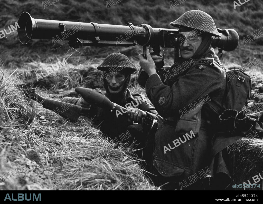 Britain's New Rocket Launcher In Action - Seen firing from a trench position is Company Sergeant Major Instructor Wilson ***** using Britain's new 3.5 Rocket Launcher - the infantryman's answer to the tank. 
The weapon - a development of the Bazooka - is being used at the Small Arms ***** School, Hythe, Kent (Note Small Arms School Corps flash) Loader who wears a visor to guard against back flash is Sgt Instructor W. Tunaley this type of weapon has had remarkable success in Korea, against tanks. February 14, 1951. (Photo by Fox Photos).