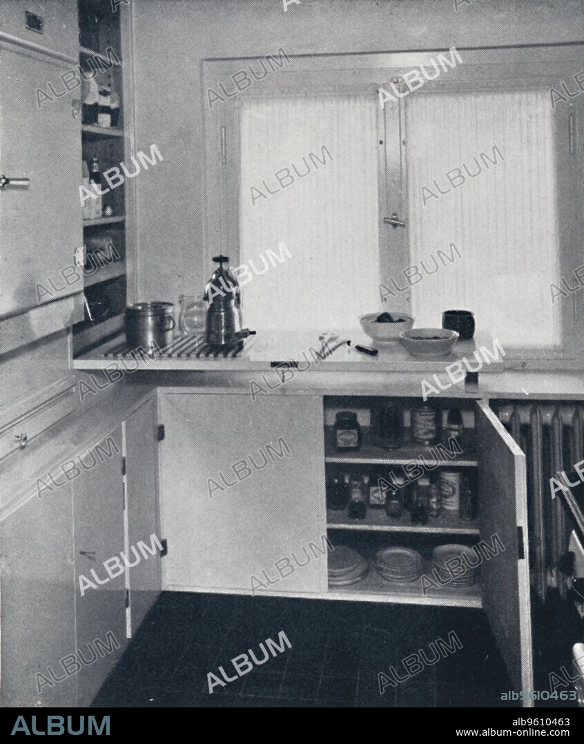 'Werner Harting - Kitchen with a black Dutch tiled floor, white walls and built-in shelves and cupboards. Also included is an electirc stove and a Frigidaire', 1939. From Decorative Art 1939 - The Studio Year Book, edited by C. G. Holme. [The Studio Ltd., London, 1939].