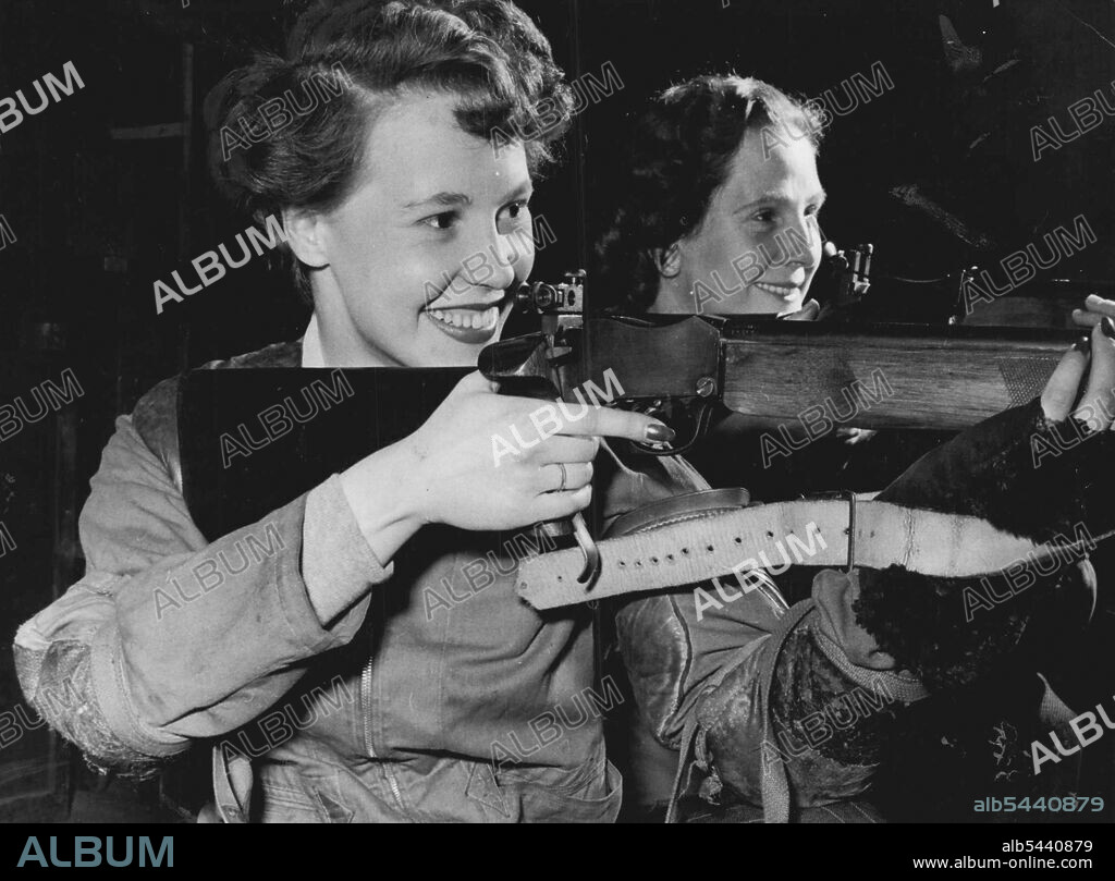 Vivacious red head Jeanette (Rusty) Townsend, twenty three year old secretary, of Balham, and wandsworth Rifle Club member, never misses her mark. She scored the maximum of 300 points with thirty bulls to win the women's individual small-bore title this year. in the background is Mrs. Margaret Gibbs, who holds the title of best shot of the year, with 100 consecutive bulls. Vivacious red head Jeanette (Rusty) Townsend 23-year-old secretary of Balham (Eng.) is member of the Wandsworth Rigle Club. She scored the maximum of 300 points with 30 bulls to with the women's individual small-bore title in England this year. November 13, 1953. (Photo by Daily Mirror).
