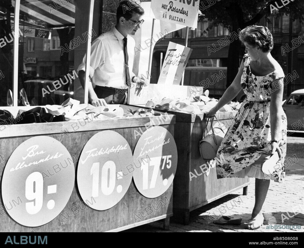 ARKIV MALMÖ 19590709.. En skoaffär utomhus i Malmö efter en idé från Frankrike. Här ses Jan M. Solow bakom disken och Fru Amanda Nicklasson som provar en sko för strandbruk.. Foto: Björn Karlin / AB Text & Bilder / SVT / Kod: 5600. Mapp: Ambulerande butiker 5503 B. Affärer Försäljning Mönster Klänningar.