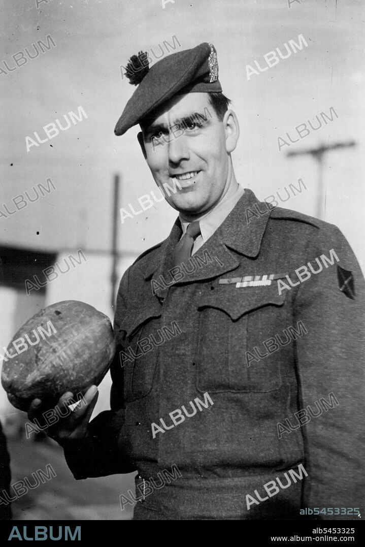 Korea V.C. Home -- Private Bill Speakman with the coconut he brought home from Korea for his kid brother Bert.Private William Speakman, who was awarded the Victoria Cross in Korea, was greeted by the Mayor of his home town Altrincham, Cheshire, when he arrived from the Far East at Lyneham Airport to-day. January 29, 1952. (Photo by Daily Mail Contract Picture).