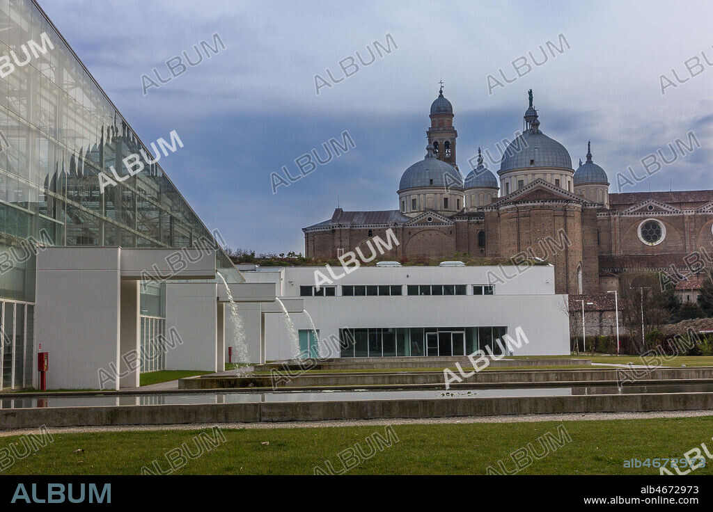 Padova, the Botanical Garden: the big greenhouse of the Garden of Biodiversity. In the background, the Basilica of St. Giustina.