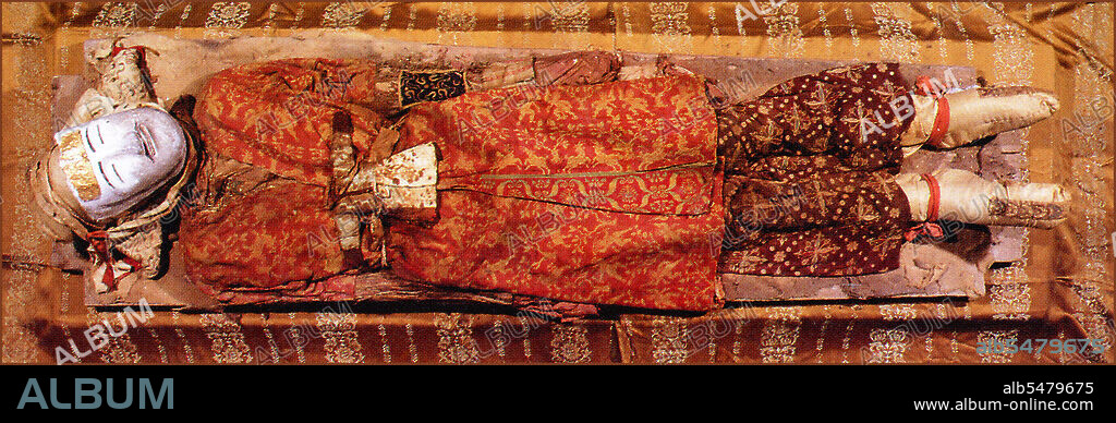 The best preserved of the corpses discovered at the cemetery at Zaghunluq in the Tarim Basin, is the 'Yingpan Man'. The two metres tall, 2,000 year old Caucasian mummy was discovered in 1995. His face was blond and bearded and was covered with a gold foil death mask; he also wore an elaborate golden embroidered red and maroon wool garments with images of fighting. His head rests on a pillow in the shape of a crowing cockerel. The Zaghunluq cemetery contained 29 mummies, dating from 1800-500 BCE.