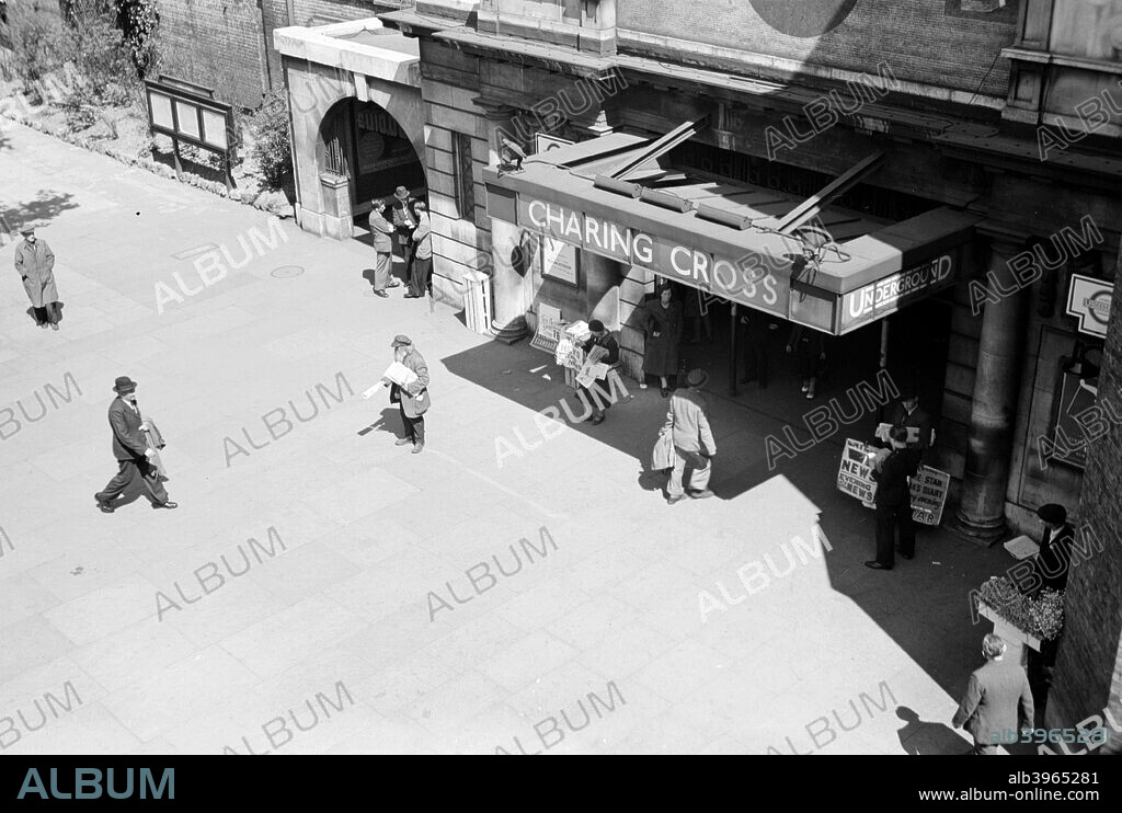 Entrance to Charing Cross Tube Station, London, c1945-c1965. Looking down on the station showing people walking into the entrance. The evening newspapers are already on sale outside. Before the Jubilee line was built Charing Cross served the Bakerloo and Northern Lines only.