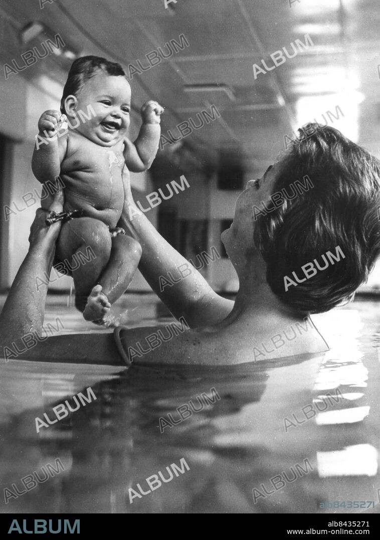 Orig. bildtext... When you are just 17 weeka old, it's a bit young to start setting swimming records, but so far neither age nor water has worried Andrea Timmermans. And it shouldn't! Tim and Claire Timmermans of Mentone, Victoria, must hold the record for being Australia's youngest water baby. She went for her first swim when she was sixteen days old. For three week after coming home from hospital, she splashed abouth in the bath, She then graduated to her parents' indoor heated swimming pool, where she has been making remarkable progress. Andrea can now swim about two yards on her stomach, and can float indefinetely on her back. Her mother, who has been a swimming coach for nine years, says she has always been interested in teaching babies to swim. Photo shows: This is fun, gurgles Andrea as she plays with her mother in her parents indoor heated swimming pool. Although Andrea has no fear of the water her parents have to support her head because her neck muscles are not yet strong enoug to keep her hands out of the water. Mrs Timmermans, who has been a swimming coach for nine years, says she always been interested in teaching babies to swim. Anm. CD162 persons: Andrea Timmermans sites: AUSTRALIEN.
