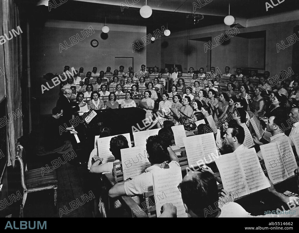 La Scala Strike Ends -- The La Scala choir in rehearsal under its conductor and trainer Veneziani.The Chorus and Orchestra of La Scala, Milan, ended their ten day strike on Wednesday.The strike concerned their right to make recordings. They have agreed to work exclusively for the Opera House from January 1, 1953.Sir Thomas Beecham was to have conducted a concert in La Scala last week but this had to be cancelled on account of the strike. October 17, 1952. (Photo by Paul Popper).