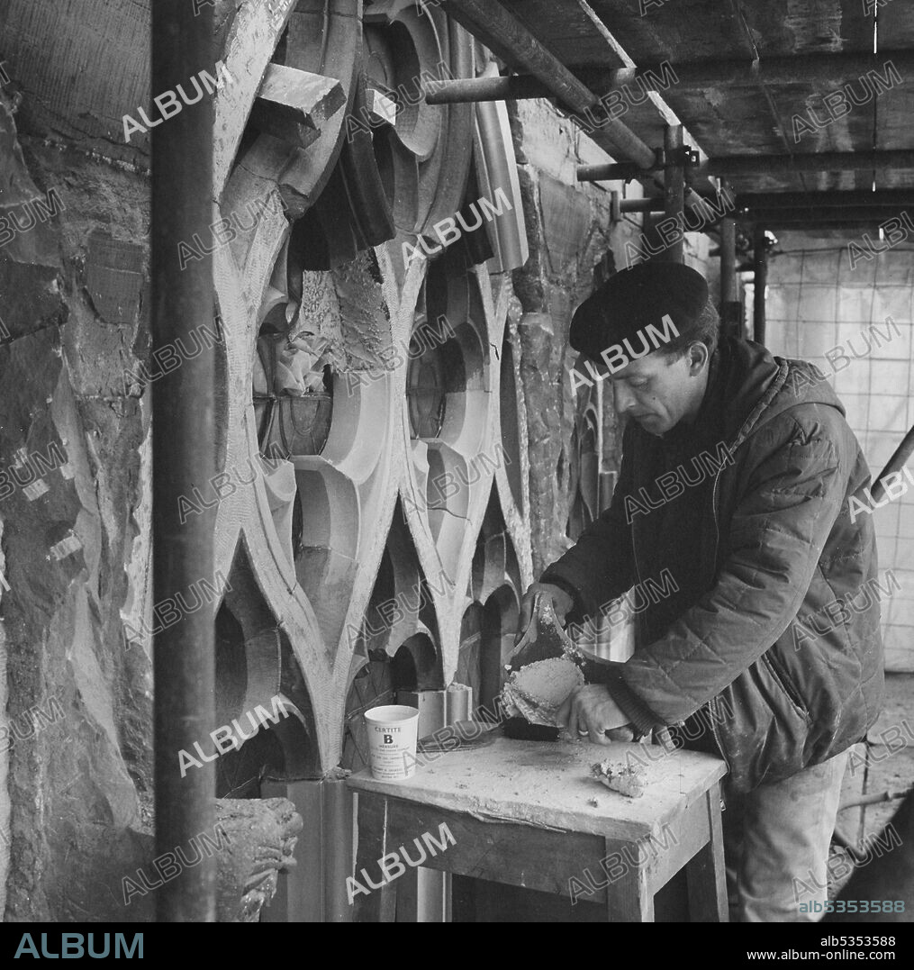 JOHN LAING PLC. A stonemason working at Carlisle Cathedral applying SBD Certite during restoration on the tracery of a window. This photograph is part of a batch taken by Laing to show restoration work being carried out using SBD Certite. In 1961, N M Phillips, the architect for Carlisle Cathedral started experimenting with the bonding material SBD Certite in the restoration of the cathedral. It was used on all but one of the decorated Gothic windows of the South Clerestory and by the time this photograph was taken, it was being used in the restoration of the north face of the cathedral. By using SBD Certite, Laing stonemasons were able to remove just the weathered surface of the stonework. New stone only two inches deep could be bonded to the old stone saving more of the original fabric of the building and cutting costs by a third.