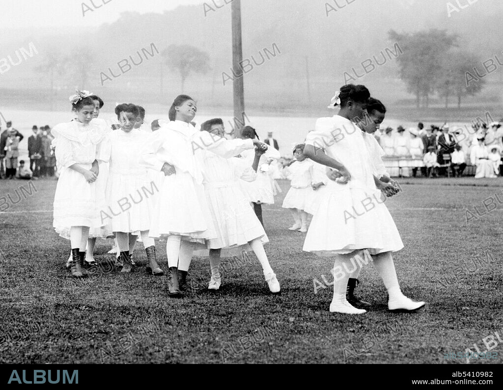 Cakewalk - Van Cortlandt Park, New York. The Cakewalk was a dance developed from the Prize Walks held in the late 19th century, at get-togethers on black slave plantations in the US. In an exhibit at the 1876 Centennial Exposition in Philadelphia, an enormous cake was awarded to the winning couple. Thereafter it was performed in minstrel shows, exclusively by men until the 1890s. The inclusion of women in the cast made possible all sorts of improvisations in the Walk, and the original was soon changed into a grotesque dance which became very popular across the country. Bain News Service, undated (cropped and cleaned).