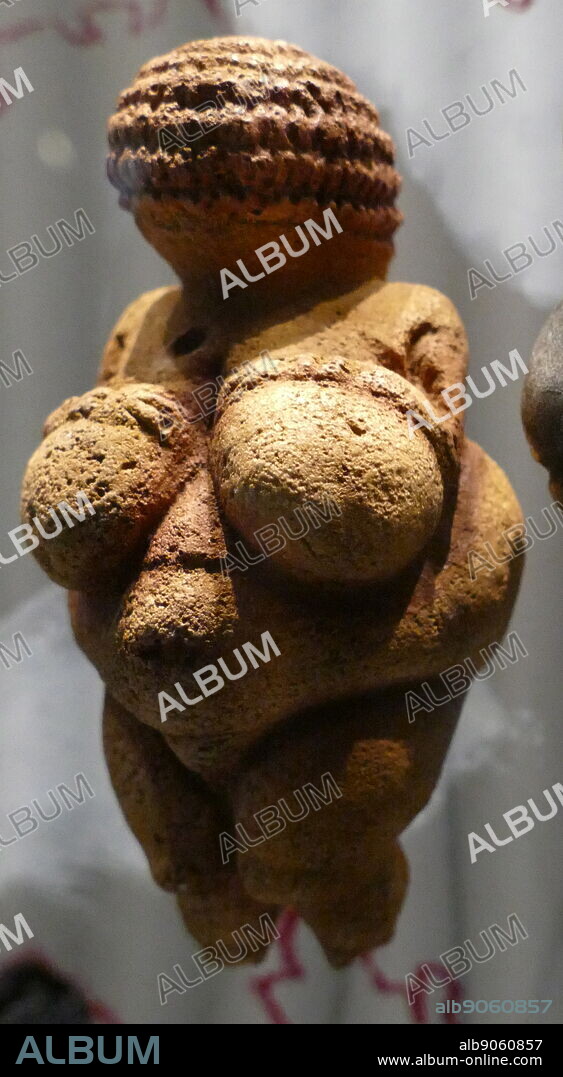 Photograph of the Venus of Willendorf, an 11.1-centimetre-high (4.4 in) Venus figurine ; made between about 28,000 and 25,000 BCE. It was found in 1908 by a workman named Johann Veran during excavations conducted by archaeologists Josef Szombathy, Hugo Obermaier and Josef Bayer at a Palaeolithic site near Willendorf, a village in Lower Austria near the town of Krems. carved from an oolitic limestone that is not local to the area, and tinted with red ochre.