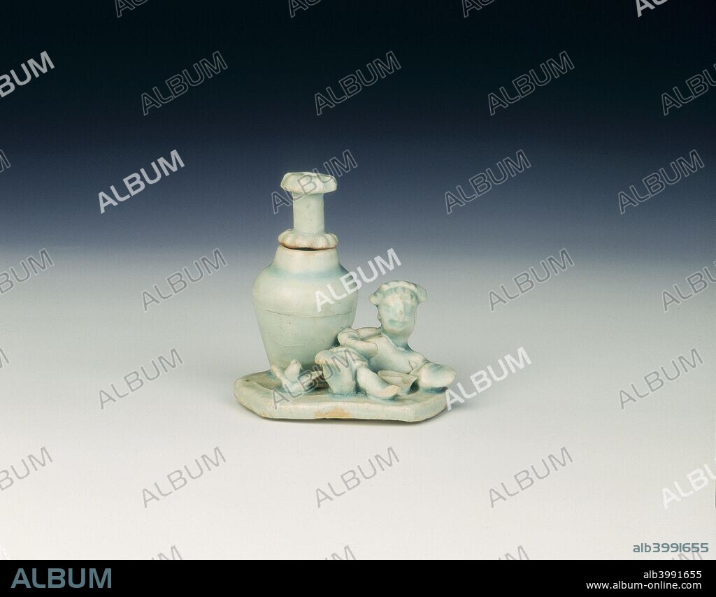Qingbai water dropper, Yuan dynasty, China, 1279-1368. Small qingbai water dropper with moulded figure of a boy reclining with legs crossed next to a large wine jar with separate hollow stopper for dropping water. Both appear on a flat hexagonal base (athough moulded underneath, as probably originally a cover for a scholar's seal paste container) with bowl and bird. The glaze has a sky blue tinge.