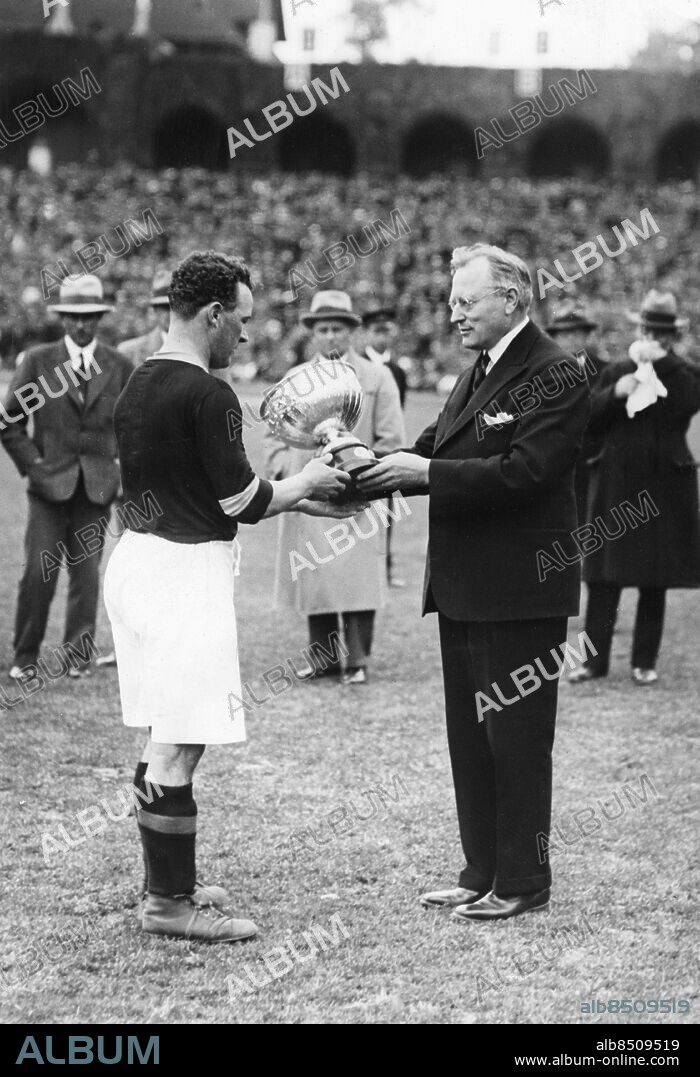 STOCKHOLM 1932-06-05. AIK:s Per "Pära" Kaufeldt tar emot von Rosens pokal av Fotbollförbundets ordförande Anton Johansson på Stockholms Stadion 5:e juni 1932 sedan AIK:s fotbollslag vunnit fotbollsallsvenskan för första gången samtidigt blev de svenska mästare för sjunde gången, Prisutdelningen tilldrog sig efter matchen mellan AIK och Gais i allsvenskans sista omgång som slutade 1-1 inför 16 819 åskådare.. Foto: Bertil Norberg / TT / Kod: 1060.