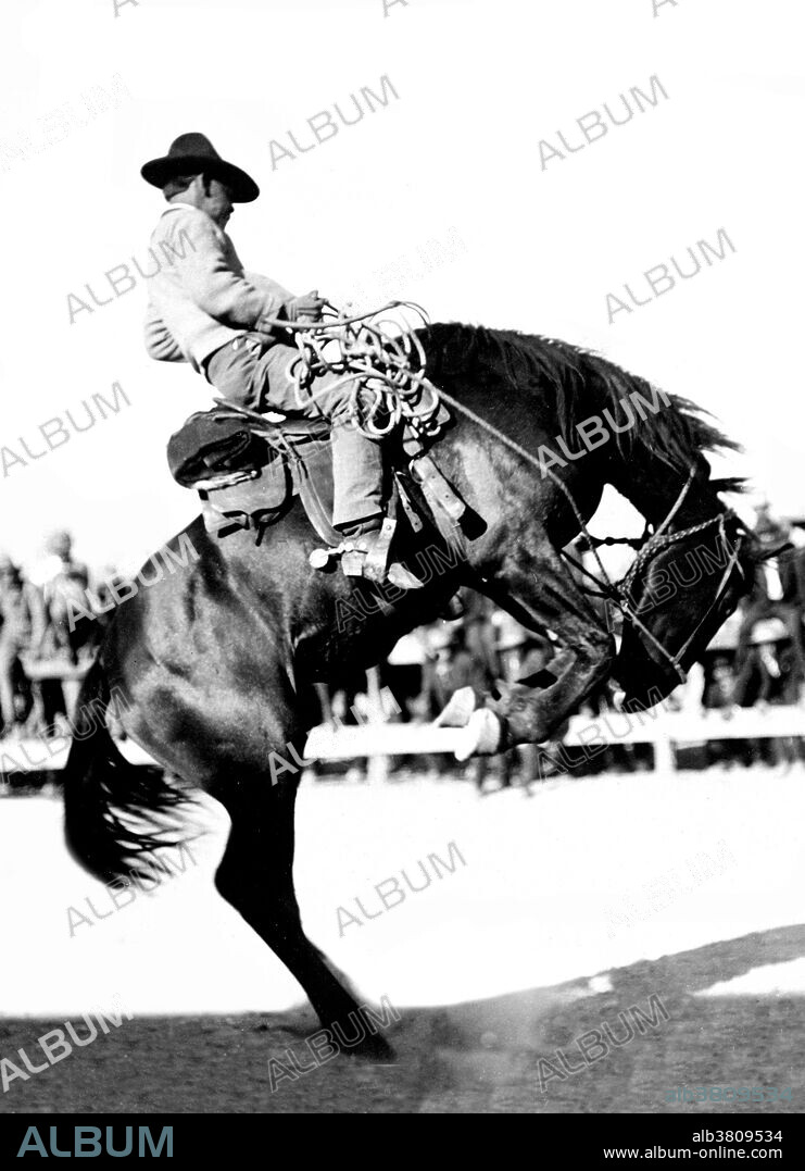 Cowboy riding a bucking bronco with spectators in the background. Cowboys of the American West developed a personal culture of their own, a blend of frontier and Victorian values that even retained vestiges of chivalry. Such hazardous work in isolated conditions also bred a tradition of self-dependence and individualism, with great value put on personal honesty, exemplified in songs and poetry. The average cowboy earned approximately a dollar a day, plus food, and, when near the home ranch, a bed in the bunkhouse, usually a barracks-like building with a single open room. Bucking is a movement performed by a horse in which the animal lowers its head and raises its hindquarters into the air, usually while kicking out with the hind legs. If powerful, it may unseat the rider enough to fall off. No photographer credited, 1910.