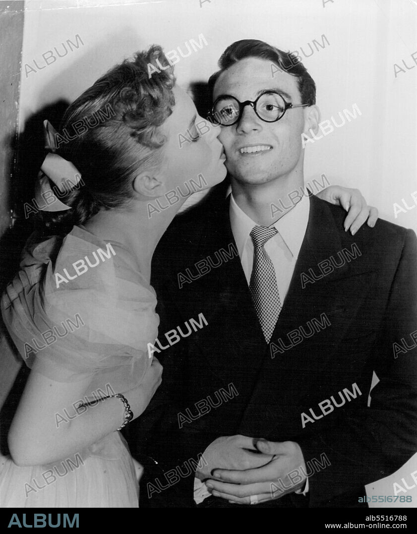 Harold Lloyd, Jr., 18-year-old son of the famed comedian - and definitely a chip off the old block as far as appearance is concerned - gets a good-luck kiss on the cheek from Movie Star Joan Evans he makes his film debut in a small part in Samuel Goldwyn's "With All My Love." Those glasses Junior's wearing are the very ones that his father made famous - brought out from the family safe deposit box for this very special occasion. September 19, 1949.
