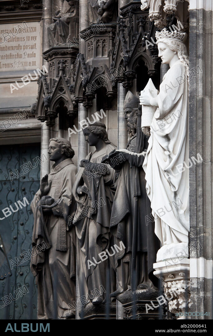 Germany, Cologne, Cologne Cathedral, South Facade, Portal of St. Peter, Jamb Sculptures. Cologne Cathedral was built was built to house the relics of the Three Magi, under the direction of Archbishop Conrad von Hochstaden. Construction of the present Gothic church began in August 15th, 1248 and completed in 1880. In 1996, the cathedral was added to the UNESCO world heritage list of culturally important sites. Seen are the portal's jamb sculptures, depicting saints representing the gifts of the Holt Ghost. from left to right: Thomas of Aquinas- wisdom; Ursula- fear of the Lord and Albertus Magnus- counsel.