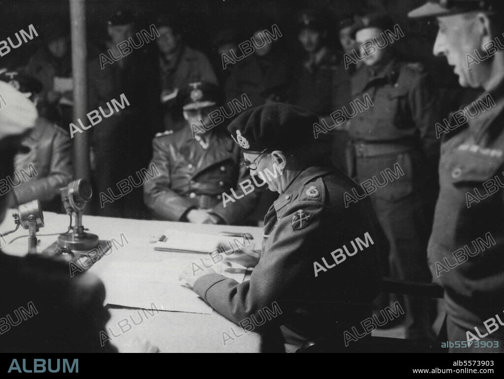Germans Surrender To Montgomery: Field Marshal  Montgomery signing the Instrument of surrender document. In the background is General Admiral Von Friedeburg, Supreme Commander of the Germen Navy.At 6.25 P.m. on May 4th, in an ordinary Army hut at 21st Army group H.Q.  on May Lunsberg Heath, 5 German Plenipotentiares in the presence of Field Marshal Montgomery put their signatures to the surrender of the German land, sea and air force in Northern Germany, Holland and Denmark. This historic picture was taken during the signing of the surrender. May 04, 1945. (Photo by Planet News Ltd.).