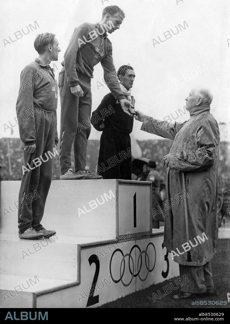 STORBRITANNIEN LONDON 1948-08-06.. Tre löpare på prispallen efter finalen på 1500 m vid de olympiska sommarspelen 1948. Guldet vanns av Henry Eriksson, Sverige, silvret av Lennart Strand, Sverige, och bronset av Wim Slijkhuis, Nederländerna. Prisutdelare är Sigfrid Edström, ordförande i Internationella Olympiska Kommittén (IOK).. Foto: Reuterphoto / AB Text & Bilder / SVT / Kod: 5600. Engelsk originalbildtext.. Mapp: O.S. i London 1948: Löpning 1500 m (Segrare: Henry Eriksson, 2:a L. Strand)(Sverige) I:275i. Prisutdelningar Prispallar Vinnare Segrare.