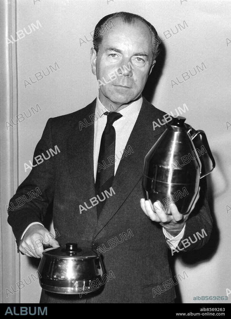 1959-09.. Orig. bildtext... SIGVARD BERNADOTTE presenterade på måndagen några husgeråd som hann gett nya och modernare former. Visningen som arrangerats av Moderna Kök upptog bl.a. en thermoskanna i rostfritt stål samt en kastrullserie med kopparbotten men i övrigt i rostfritt. -Här visar Sigvard Bernadotte upp nyheterna. 7-9-59. Anm. S. Bernadotte, 1907-2004. Framstående formgivare, illustratör och internationellt erkänt industridesigner. Kastruller Termosar Termoskannor Formgivning Design persons: SIGVARD BERNADOTTE sites: SVERIGE.