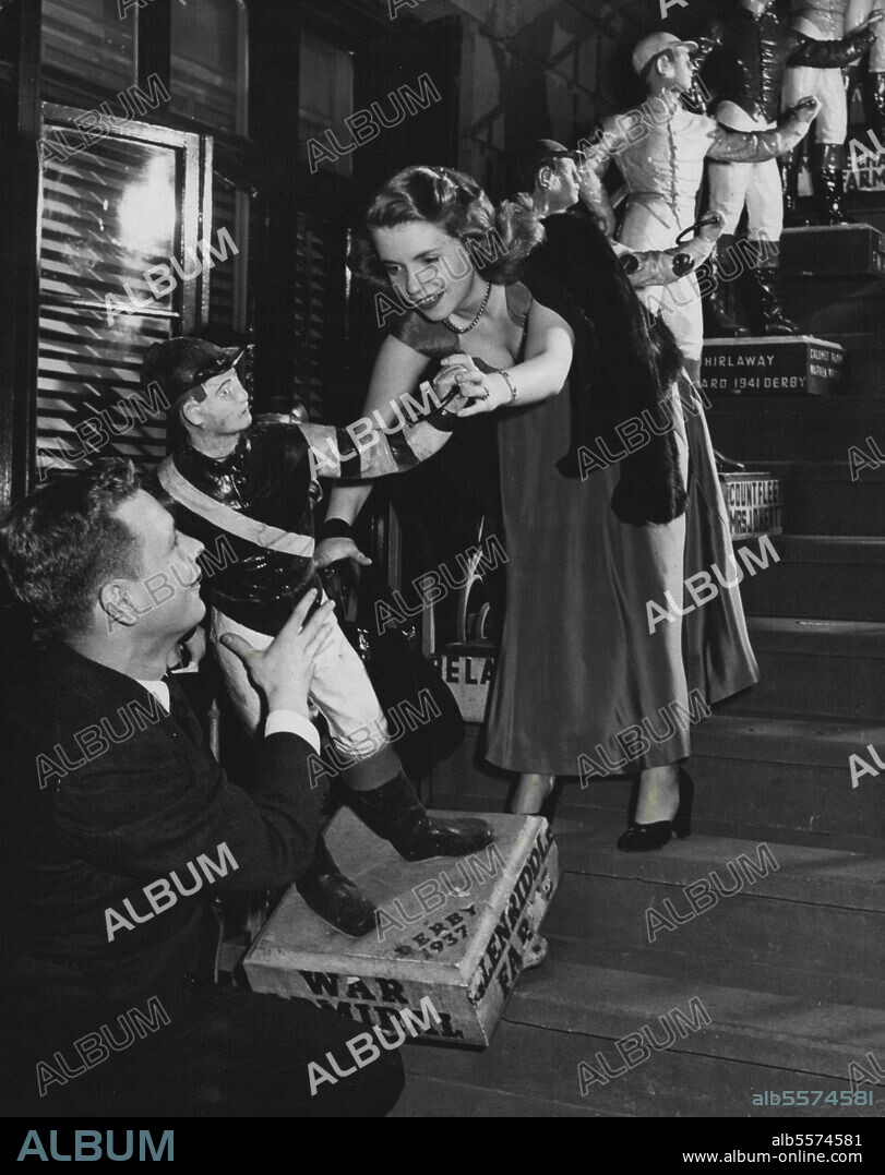 Return with one of jockeys on the steps of the 21" Club.Howard Marton, Claire Kahn sweated and strained and barely budged the jockey on the steps of the 21" Club before they gave up. The couple complained: Nobody told us these things are made out of solid pig iron." July 13, 1948.