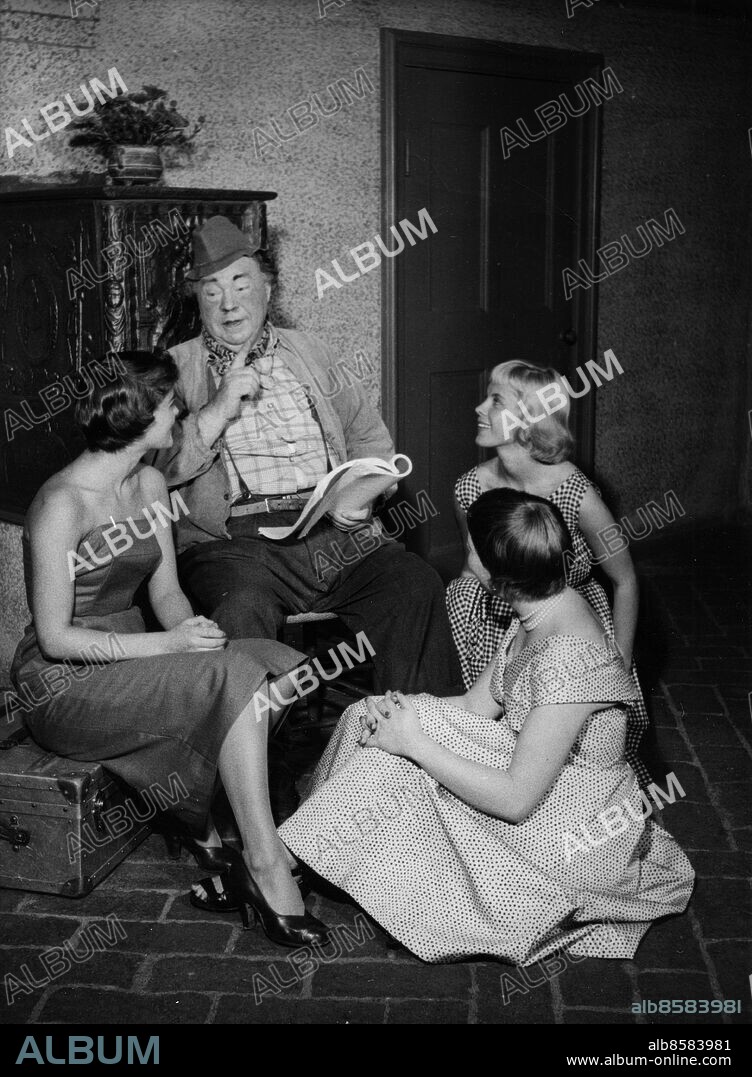 ARKIV CA 19540817. Den skånske sångaren och skådespelaren Edvard Persson läser sagan om Glimmingehus för skådespelerskorna fr.v. Gunilla Åkerréhn, Brita Ulfberg och Bibi Andersson. Edvard gjorde på tisdagen sitt första framträdande framför filmkameran på två år, iklädd hatt och 23 kilo lättare.. Foto: Svenskt Pressfoto / SCANPIX / Kod: 20360.