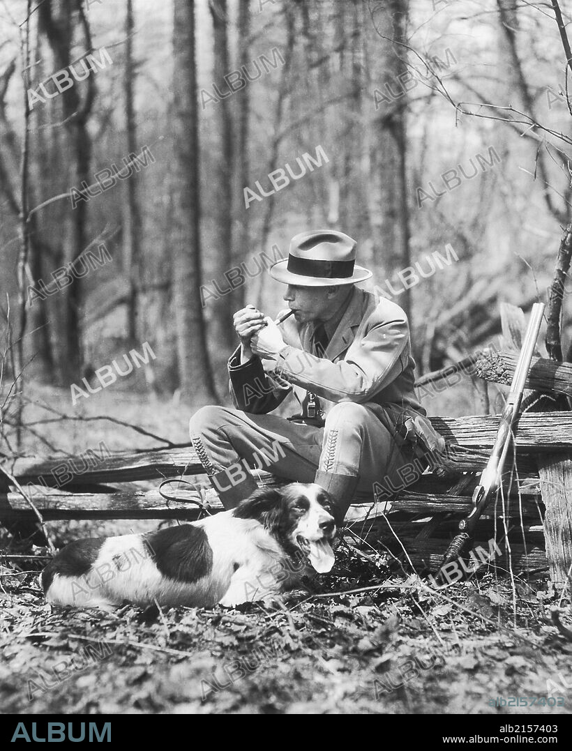 Hunter smoking pipe while resting with dog.