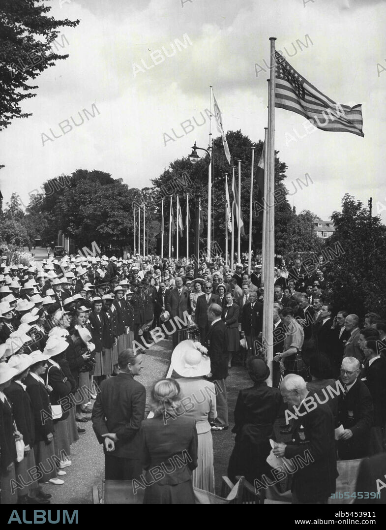U.S. Flag is Raised At Uxbridge : As the American Flag is secured by a kilted attendant, after being raised by Mrs. Lewis Douglas, wife of the American Ambassador (Third woman from left, back to camera, in foreground), Boery Brundage (standing, centre) president of the American Athletic Association, addresses members of the American Olympic team at the Uxbridge (Middlesex) Camp this morning, July 22. Man standing extreme left (foreground, back to Camera) is the right honourable Lord Burghley, chairman of the organising committee for the Olympic games. Behind him, a little to the right, is Miss Sharman Douglas, daughter of the American Ambassador. July 22, 1948. (Photo by Associated Press Photo).